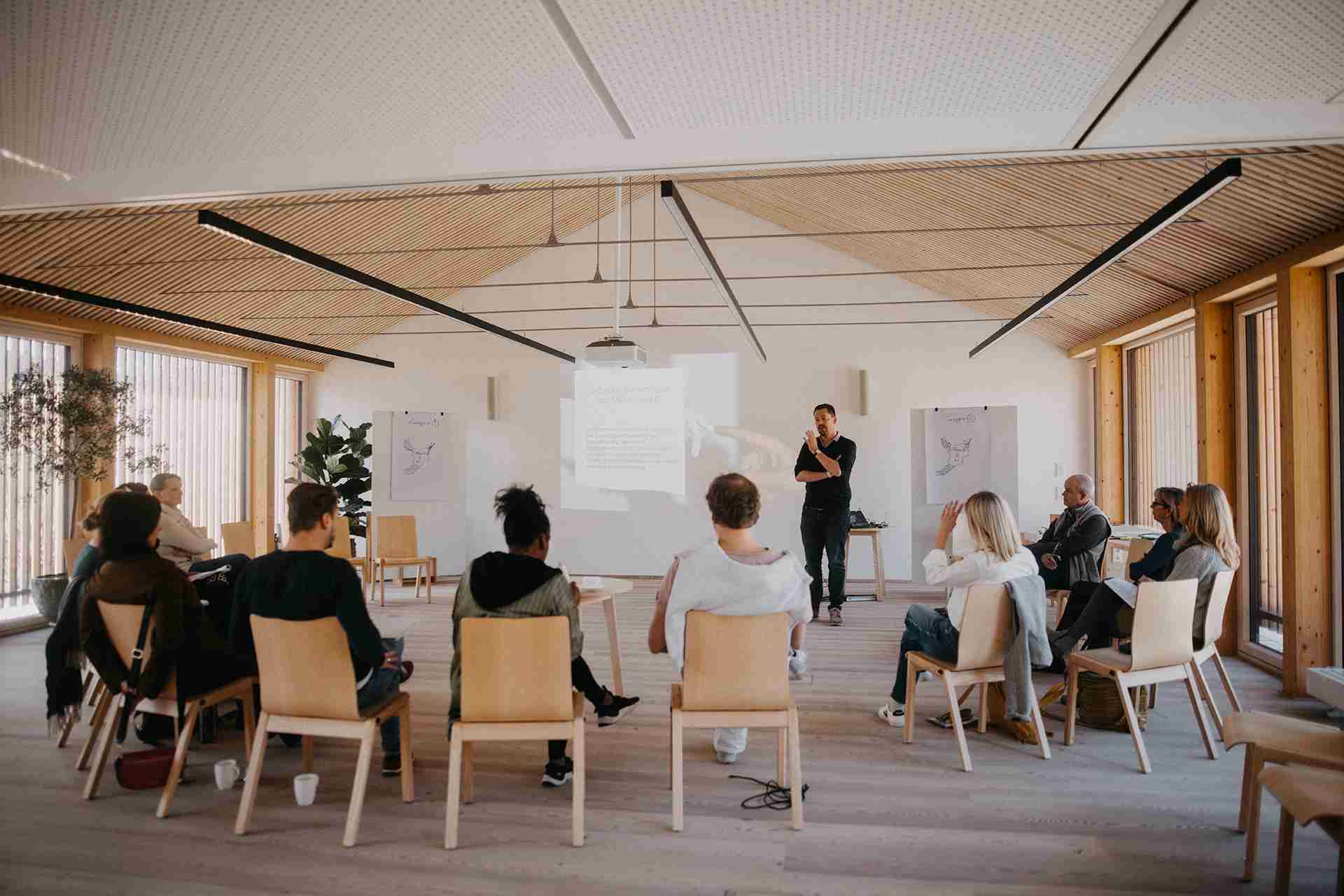 Trainer mit sitzenden Teilnehmer:innen im Kreis AI und KI