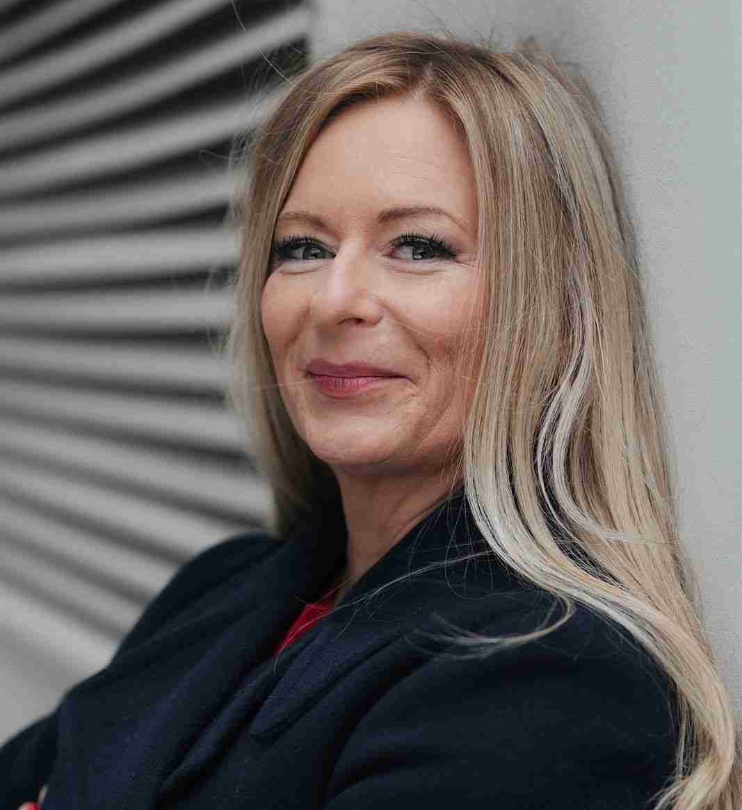 ESther Narbeshuber lächelnd an Hauswand