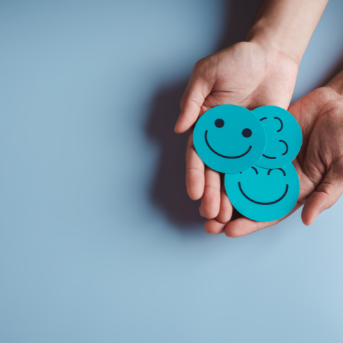 Zwei Hände halten Buttons mit lachenden Smileys im Training Resilienz