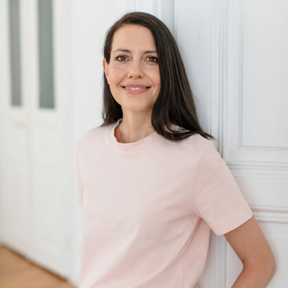 Anna Mahlodji - Mentorin Masterclass Selbständigkeit lächelnd vor weißer Türe